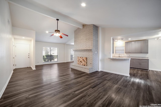 unfurnished living room featuring ceiling fan, a fireplace, lofted ceiling with beams, and dark hardwood / wood-style floors