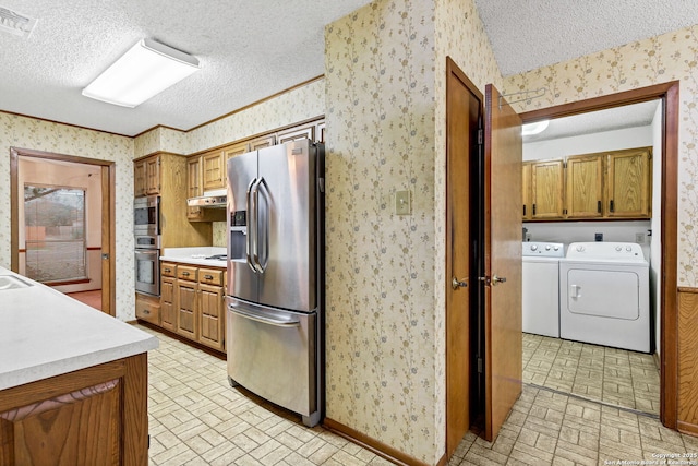 kitchen featuring appliances with stainless steel finishes, washing machine and dryer, and a textured ceiling