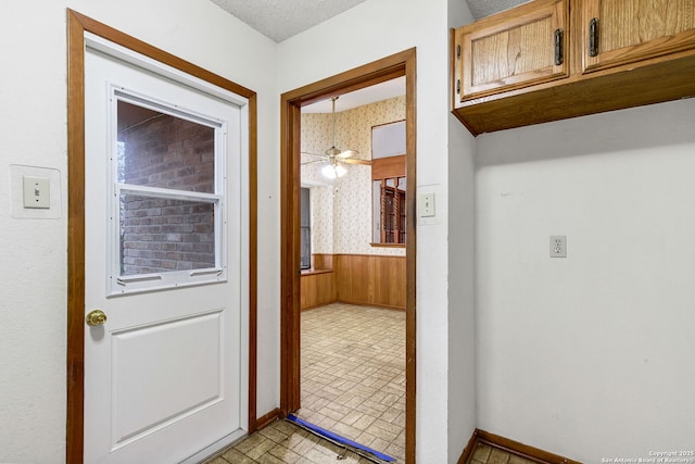 doorway featuring wooden walls and ceiling fan