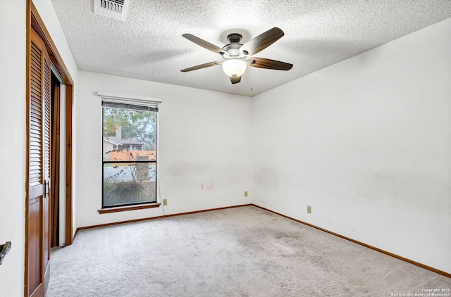 unfurnished bedroom featuring light carpet, a textured ceiling, a closet, and ceiling fan