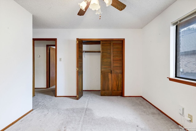 unfurnished bedroom with multiple windows, a textured ceiling, light colored carpet, and ceiling fan