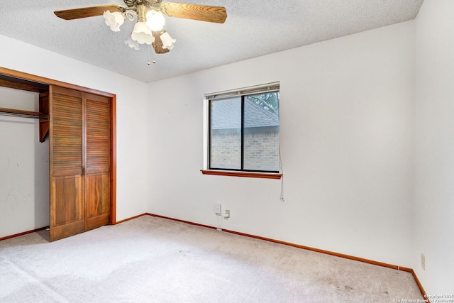 unfurnished bedroom with ceiling fan, a closet, light colored carpet, and a textured ceiling