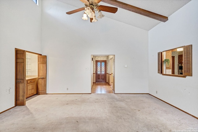 empty room featuring ceiling fan, beam ceiling, light colored carpet, and high vaulted ceiling