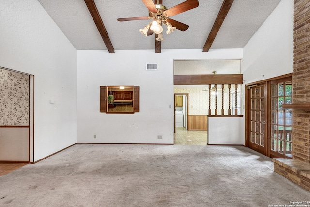 unfurnished living room with a brick fireplace, ceiling fan, a textured ceiling, beamed ceiling, and light colored carpet