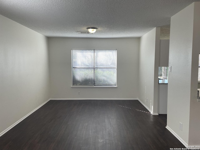 spare room featuring a textured ceiling and dark hardwood / wood-style flooring