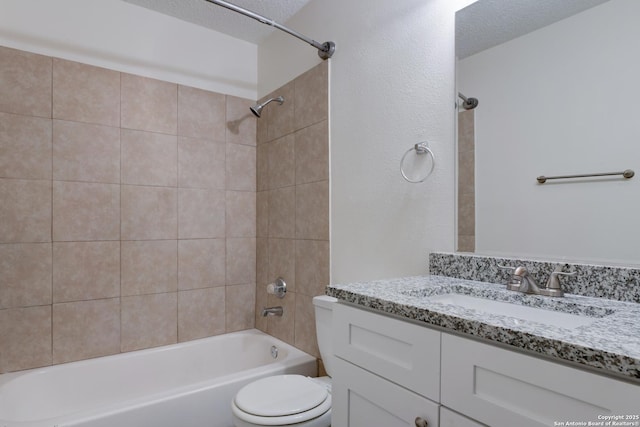 full bathroom with vanity, toilet, a textured ceiling, and tiled shower / bath combo