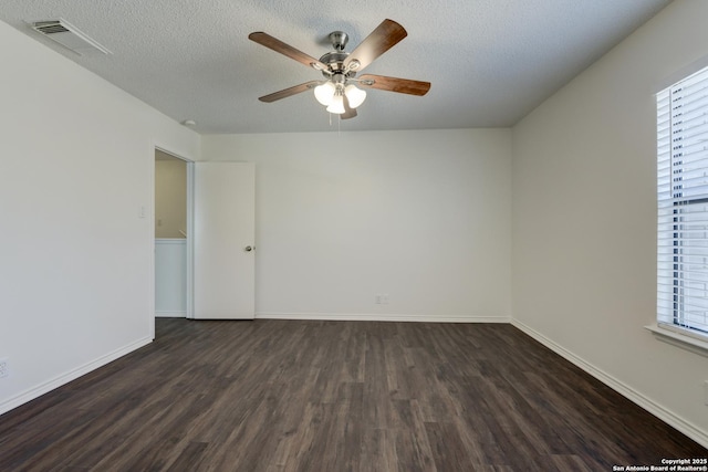 unfurnished room with ceiling fan, a wealth of natural light, dark hardwood / wood-style floors, and a textured ceiling