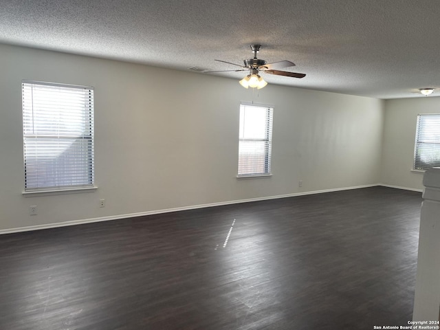 unfurnished room featuring a healthy amount of sunlight, a textured ceiling, ceiling fan, and dark hardwood / wood-style flooring