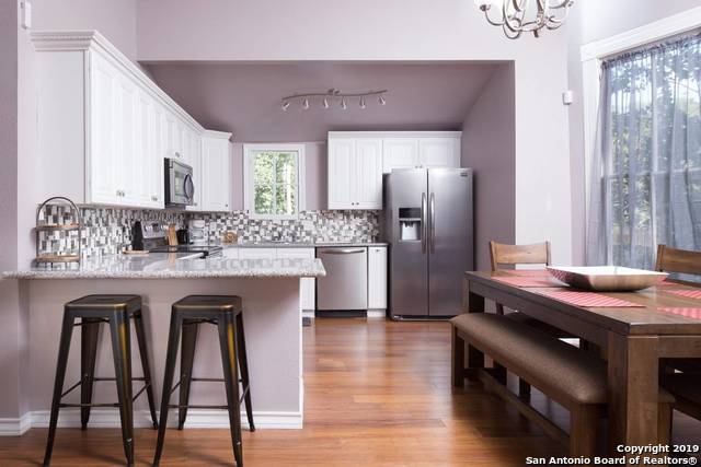 kitchen with backsplash, white cabinets, light stone counters, stainless steel appliances, and a chandelier