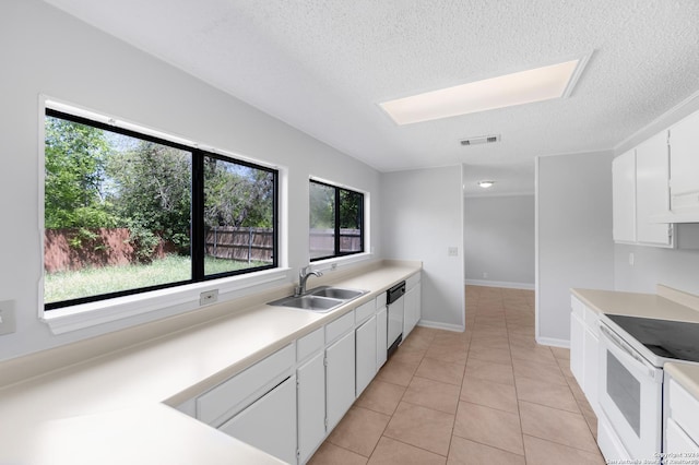 kitchen with electric stove, sink, light tile patterned floors, a wealth of natural light, and white cabinetry