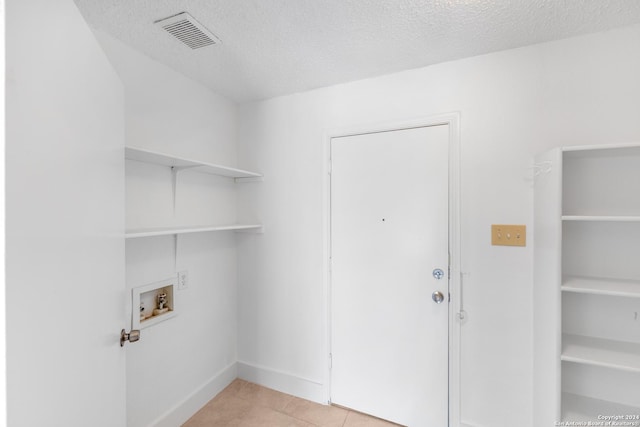 laundry room featuring hookup for a washing machine, a textured ceiling, and light tile patterned floors