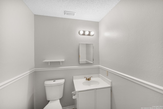 bathroom with vanity, a textured ceiling, and toilet