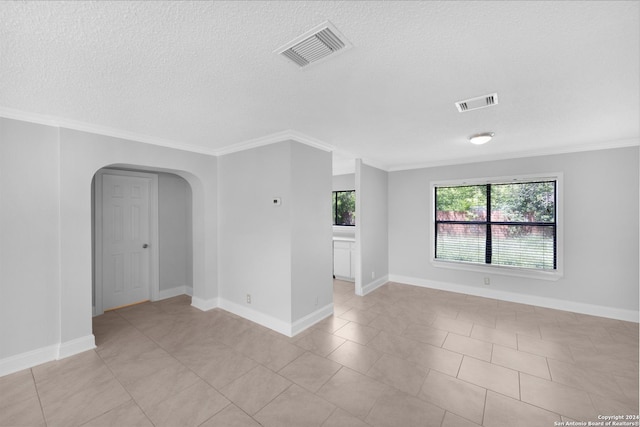 tiled spare room featuring a textured ceiling and crown molding