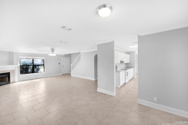 unfurnished living room featuring ceiling fan, light tile patterned flooring, a textured ceiling, and ornamental molding