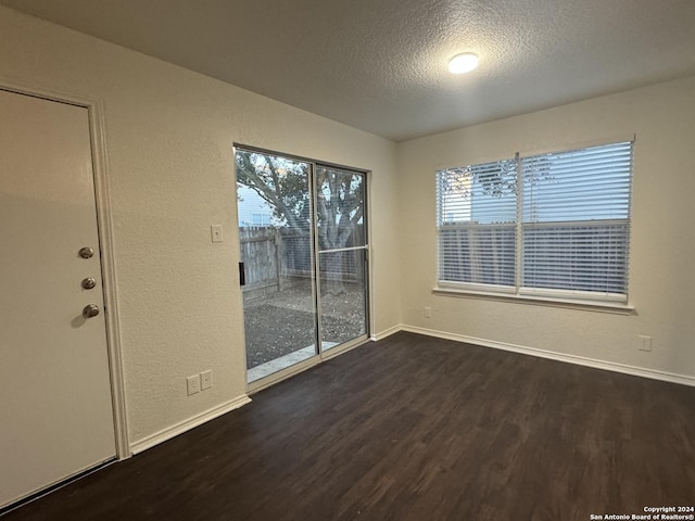 unfurnished room with dark hardwood / wood-style floors, a textured ceiling, and a wealth of natural light