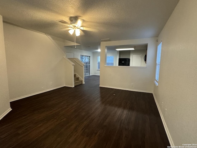 unfurnished living room featuring a textured ceiling, ceiling fan, and dark hardwood / wood-style floors