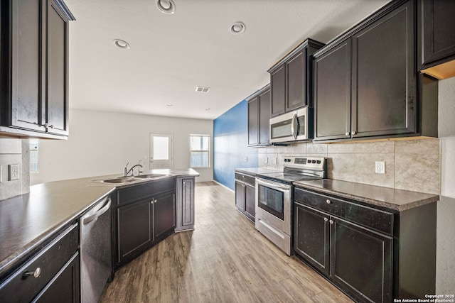 kitchen featuring decorative backsplash, sink, stainless steel appliances, and light hardwood / wood-style flooring