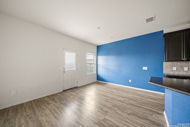 interior space with wood-type flooring and tasteful backsplash