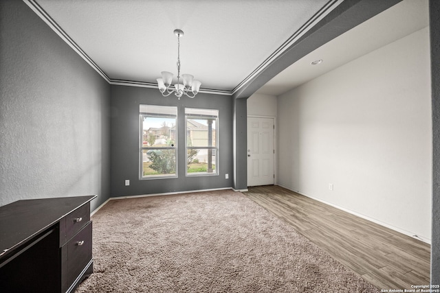 unfurnished room featuring a chandelier, light wood-type flooring, and crown molding