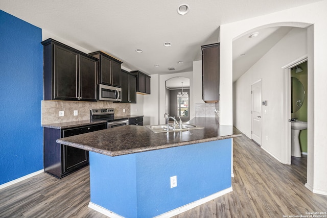 kitchen featuring kitchen peninsula, tasteful backsplash, stainless steel appliances, sink, and wood-type flooring