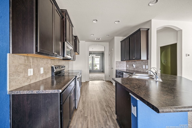 kitchen featuring sink, stainless steel appliances, light hardwood / wood-style flooring, a notable chandelier, and dark brown cabinets