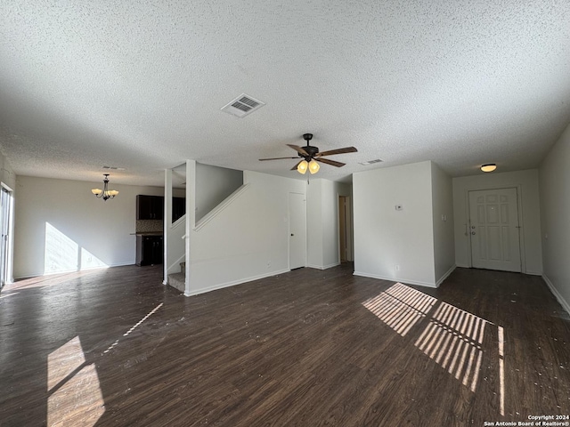 unfurnished living room with a textured ceiling, dark wood-type flooring, and ceiling fan with notable chandelier