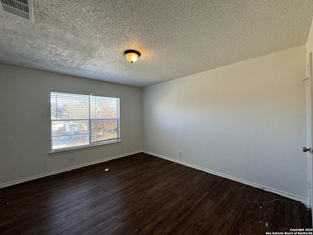 unfurnished room with dark hardwood / wood-style flooring and a textured ceiling