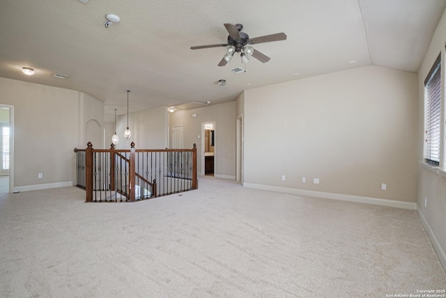 carpeted spare room with ceiling fan with notable chandelier and lofted ceiling