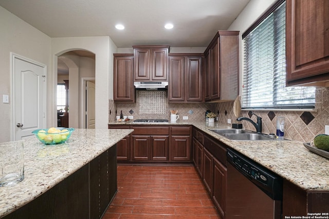 kitchen featuring dark brown cabinetry, stainless steel appliances, light stone counters, and sink