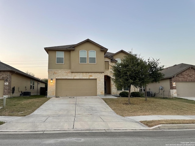 front of property featuring a yard, a garage, and central AC unit