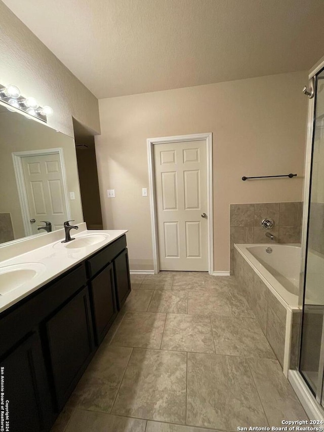 bathroom with tile patterned floors, vanity, and tiled bath