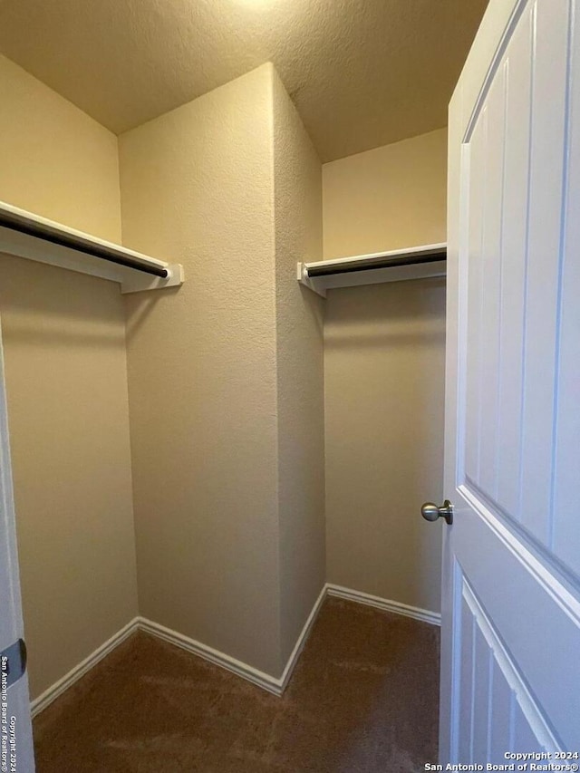 walk in closet featuring dark carpet