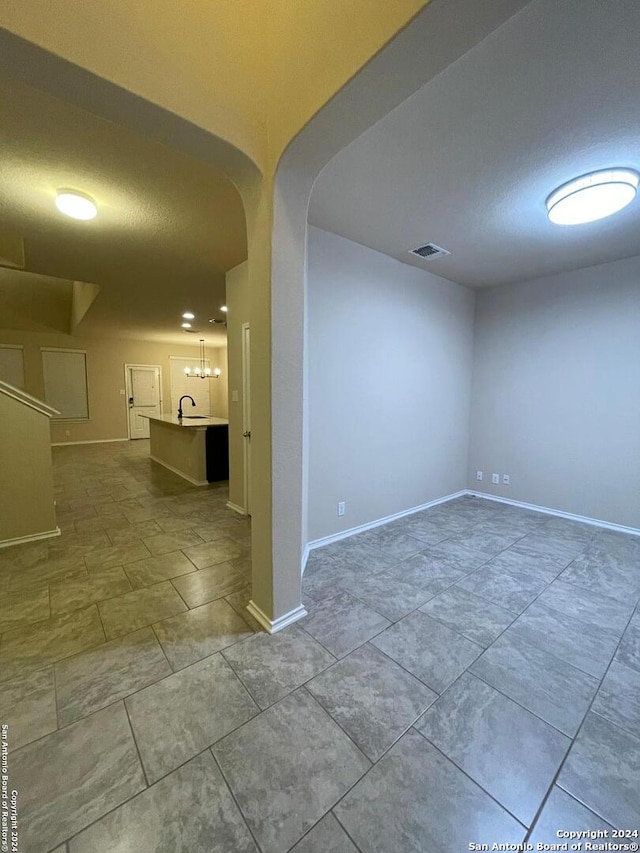 empty room featuring sink, a textured ceiling, and a notable chandelier