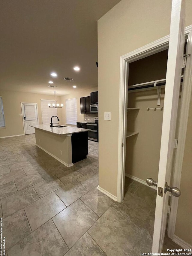 kitchen featuring sink, a notable chandelier, a kitchen island with sink, a breakfast bar, and appliances with stainless steel finishes