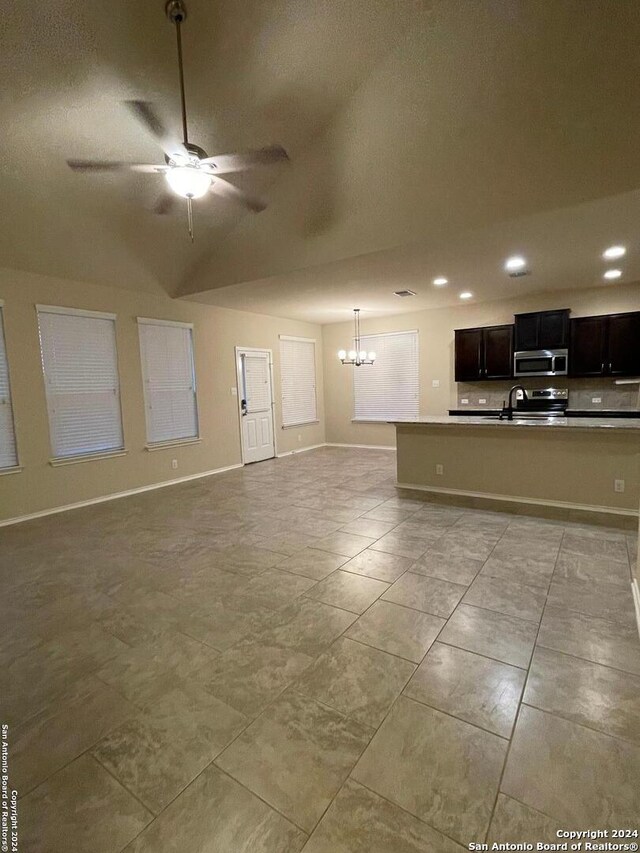 unfurnished living room featuring ceiling fan with notable chandelier and lofted ceiling