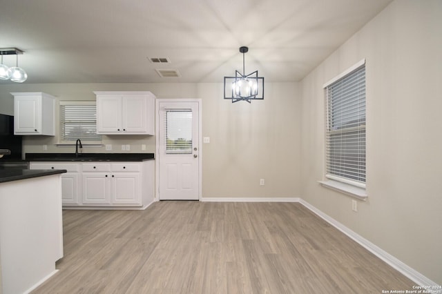 kitchen with white cabinets, sink, light wood-type flooring, decorative light fixtures, and a chandelier