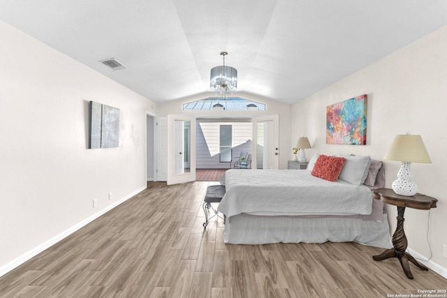 bedroom with hardwood / wood-style flooring, lofted ceiling, and a notable chandelier