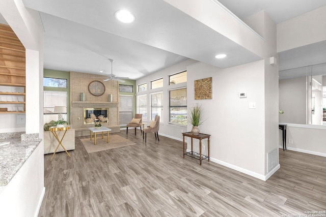 interior space featuring ceiling fan, a fireplace, and light hardwood / wood-style floors