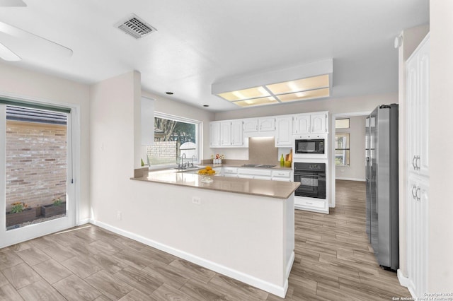 kitchen featuring black appliances, white cabinetry, kitchen peninsula, and sink