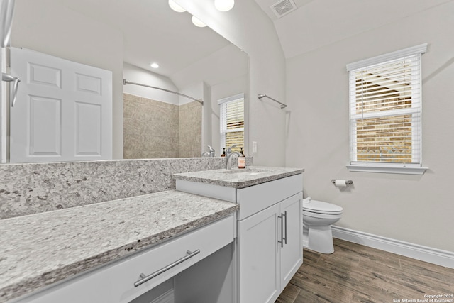 bathroom featuring a shower, wood-type flooring, lofted ceiling, toilet, and vanity