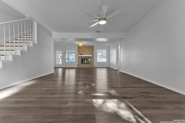 unfurnished living room with ceiling fan, dark hardwood / wood-style flooring, and a brick fireplace