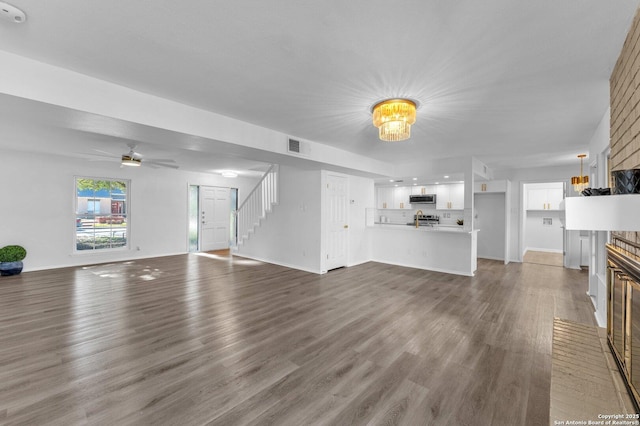 unfurnished living room with ceiling fan, dark wood-type flooring, and a brick fireplace