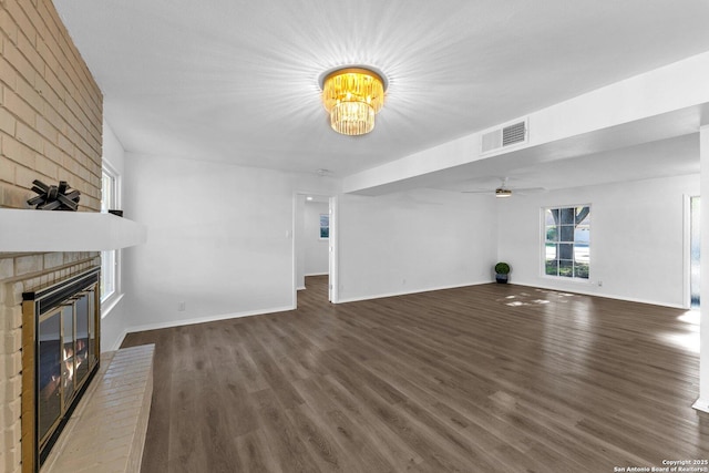 unfurnished living room featuring dark hardwood / wood-style flooring, a fireplace, and ceiling fan with notable chandelier