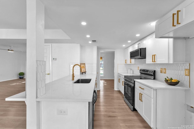 kitchen featuring stainless steel electric stove, white cabinets, sink, light stone countertops, and light wood-type flooring