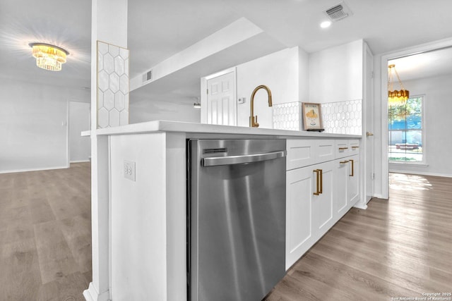 kitchen with dishwasher, backsplash, white cabinets, light wood-type flooring, and a chandelier