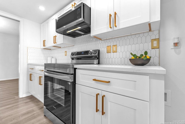 kitchen with backsplash, light stone counters, stainless steel appliances, light hardwood / wood-style flooring, and white cabinetry