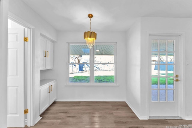 unfurnished dining area with a notable chandelier and dark wood-type flooring