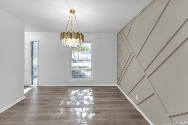 unfurnished dining area with dark wood-type flooring and an inviting chandelier