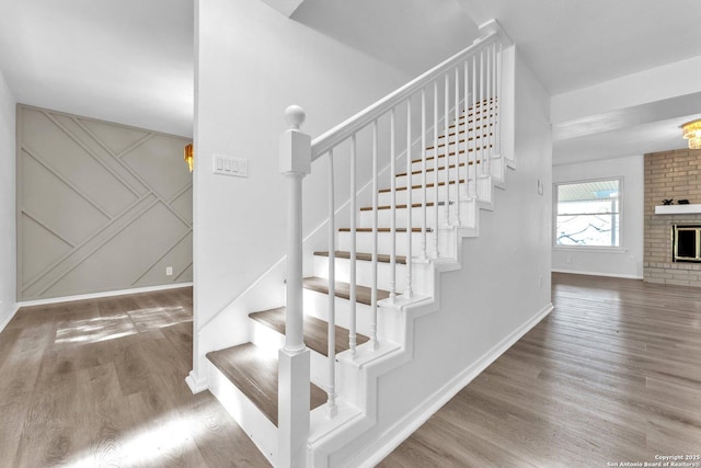 stairway with a fireplace and wood-type flooring