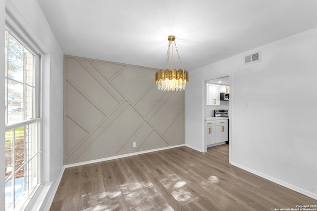 unfurnished dining area with light hardwood / wood-style flooring and an inviting chandelier